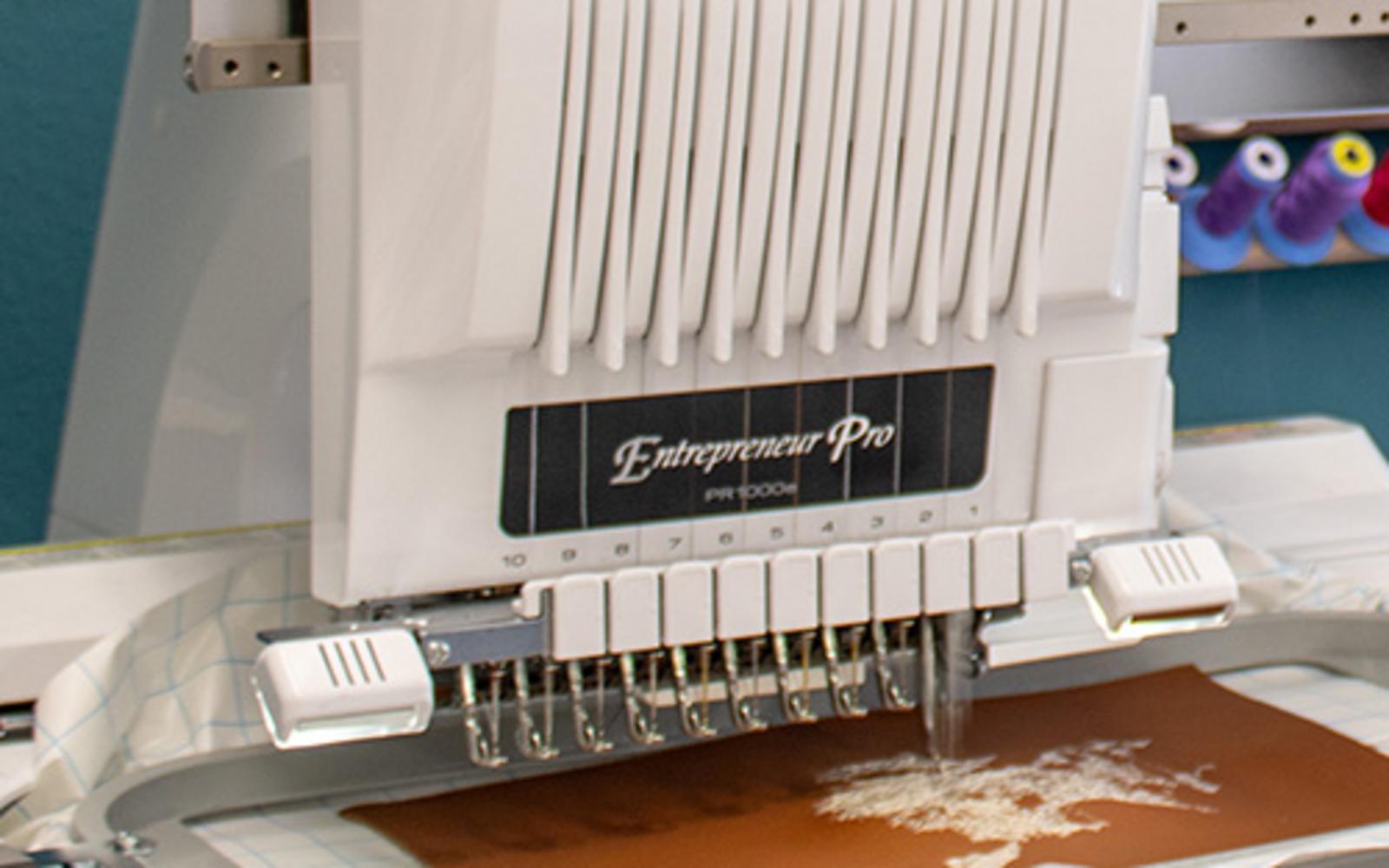 Stickmaschine bei der Arbeit auf braunem Stoff