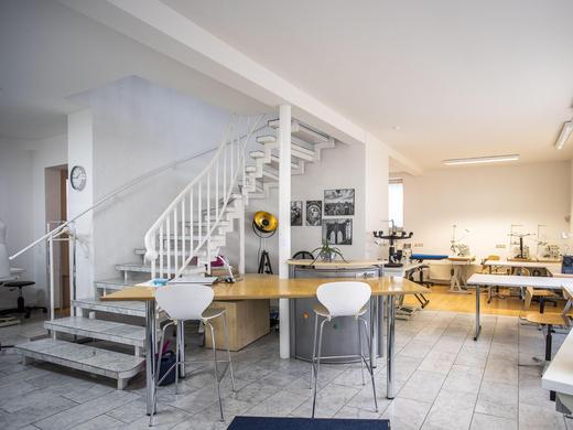 Nähatelier Start-Up - Eingangsbereich mit Treppe nach oben, Nähmaschinen, Stühlen und dem Lehrerpult.