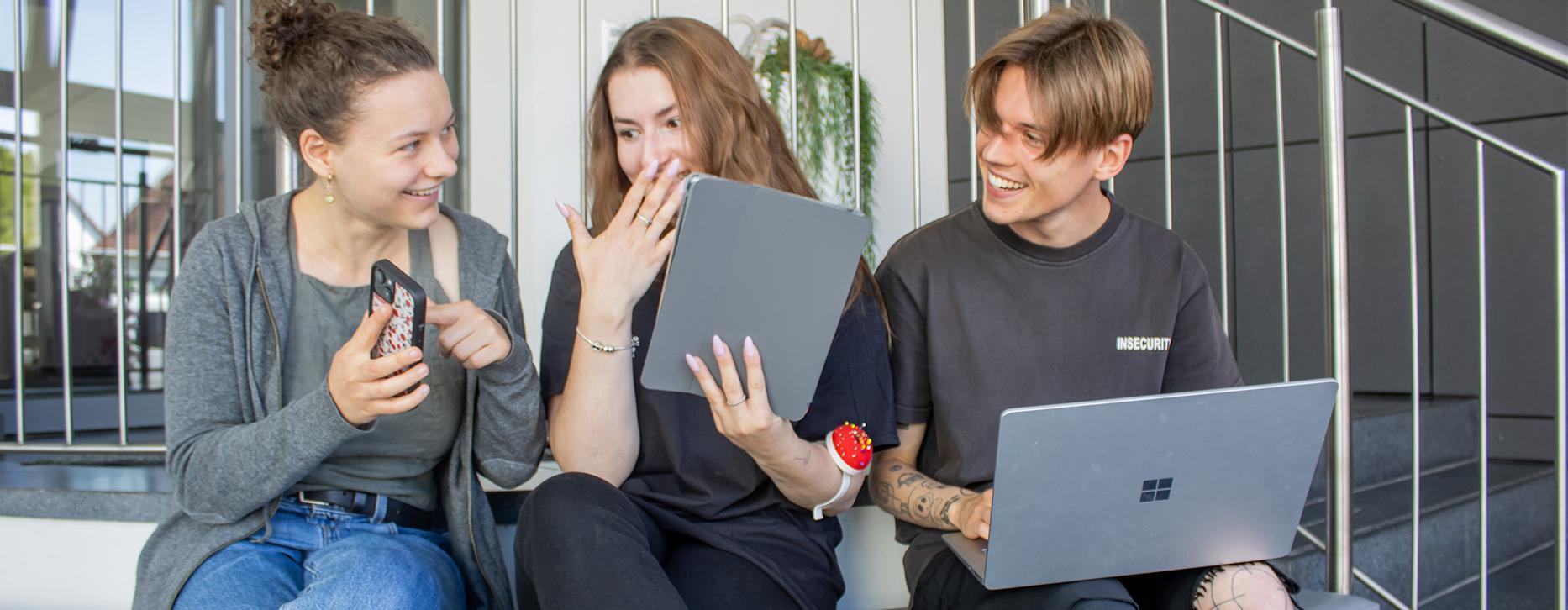 drei junge Leute sitzen nebeneinander und suchen nach Jobangebote