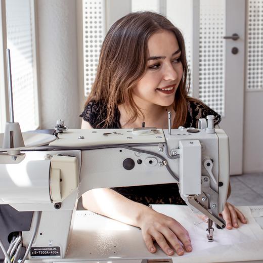 junge Frau sitzt an der Nähmaschine