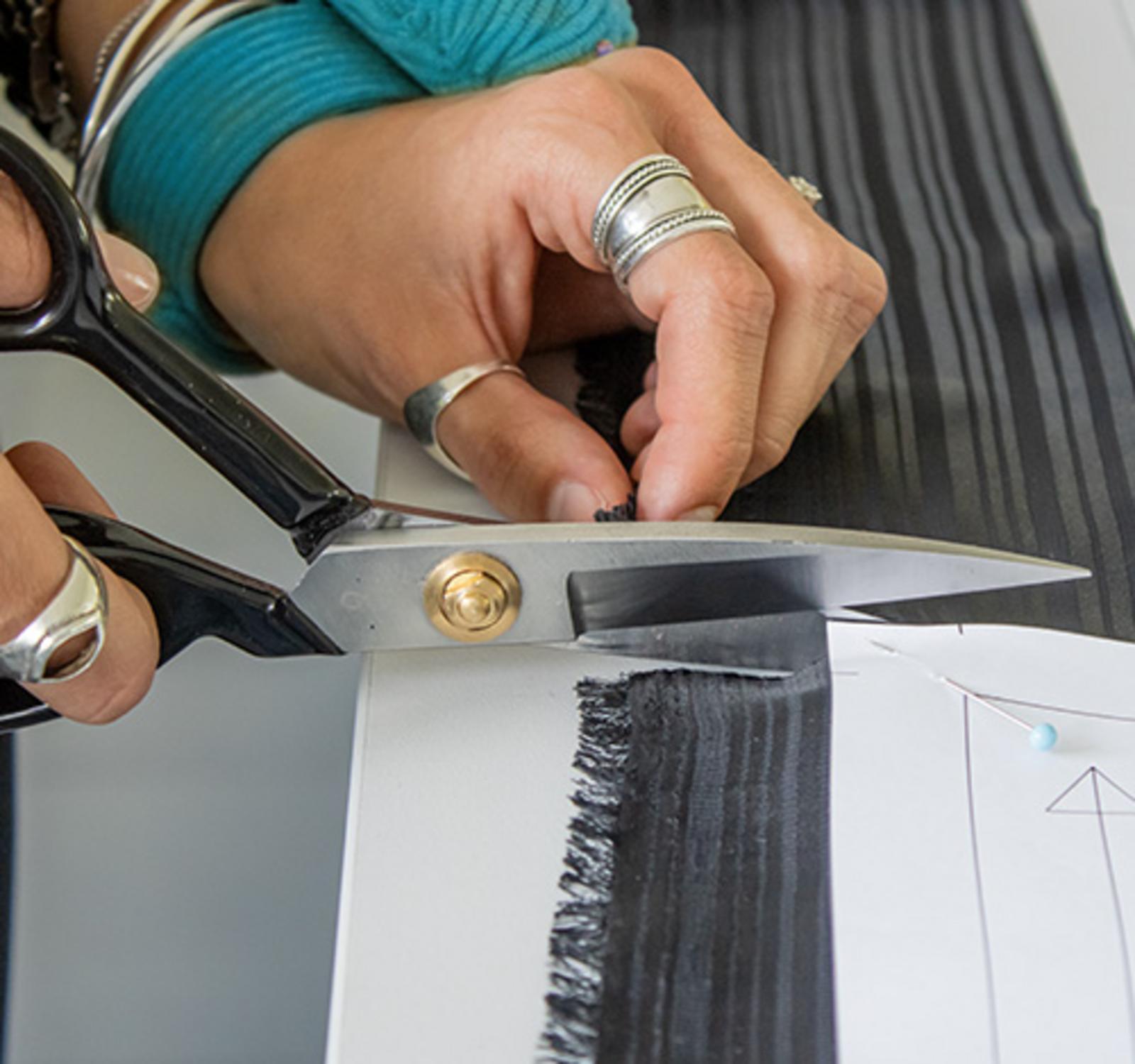 Nahaufnahme: Hände schneiden Stoff entlang eines Schnittmusters