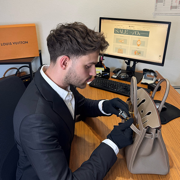 junger Mann bei der Qualitätskontrolle einer Designertasche